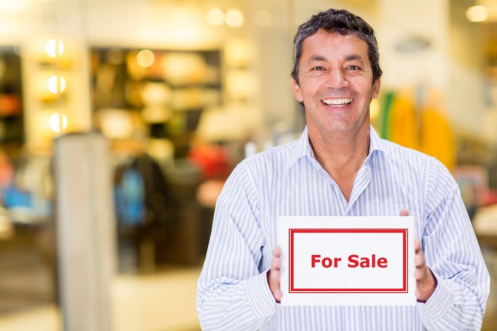 Male business owner holding an open sign and smiling